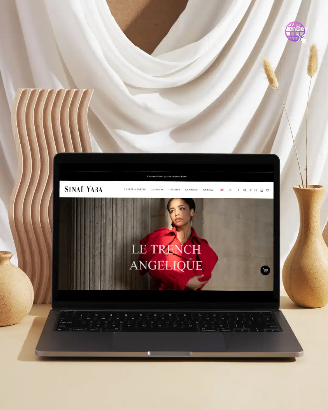 Refonte site internet WordPress et Woocommerce par WenDev et Céline Gana - Sinaï Yaba. Mockup du nouveau site internet avec un ordinateur portable posé sur une table marron avec un décor composé d'un voile blanc et de vases décoratifs beiges.