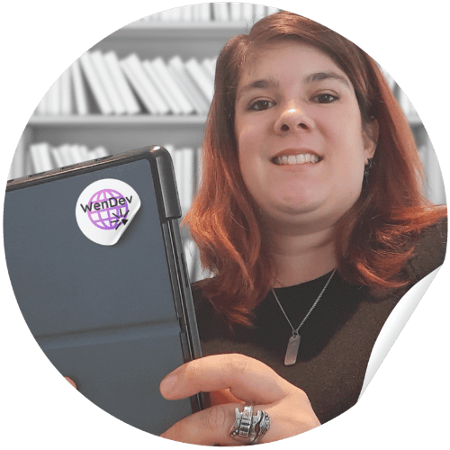 Photo de WenDev - Wendy Baqué qui tient son ordinateur devant une bibliothèque. Photo de WenDev - Wendy Baqué qui tient son ordinateur devant une bibliothèque.